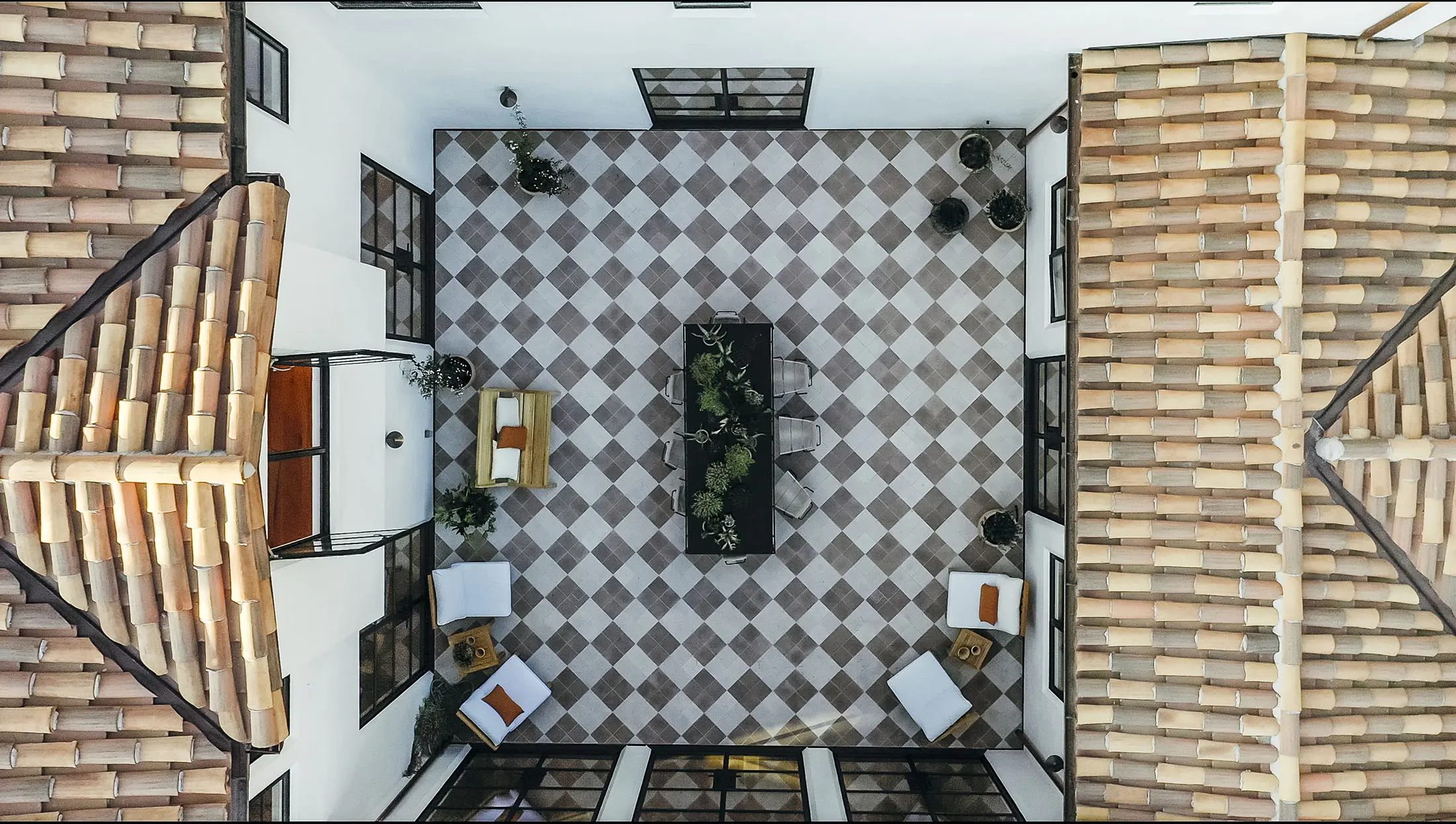 A modern living room with a neutral color palette. Features include a cream sofa, two pink chairs, a round black coffee table, and a large fireplace. Above the fireplace is a bold abstract painting. The space is bright, with light wood floors and large windows enhancing the open layout.